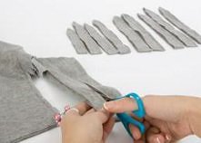 1.Zacznij od złożenia materiału ze starej koszulki na pół i wycięcie z niego pasków o szerokości 1 cm. Wytnij po 3 zestawy pasków o jednakowych długościach, na przykład 3 paski ...