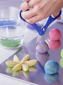 Roll a ball of sugar cookie dough in colored sugar. Snip it in half with scissors, then snip each half into three petals. Gently spread the petals apart and lay flat.