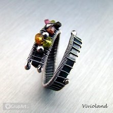 Wielobarwny pierścionek srebrny z turmalinami. Wykonany techniką wire-wrapping, oksydowany i polerowany. Regulowany: wielkość od 18 do 23 (średnica wewnętrzna: 18,33mm - 20mm).T...