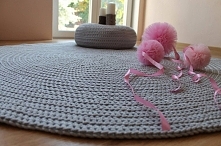 Okrągły dywan dziergany na drutach w modnym kolorze szarości.