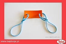 Następnie przeciągnij przez każdą dziurkę jedną gumkę i przełóż je tak, jak pokazano na zdjęciu.