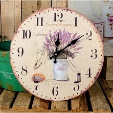 Zegar prowansalski, którego tarcza posiada jasne tło, bukiet lawendy w metalowym naczyniu. Całość lekko postarzana. Ta dekoracja dodaje Niesamowity urok na ścianie.