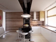 W pomieszczeniu zastosowano duże płaszczyzny ciepłego, naturalnego drewna, które stanowi tło dla czarnej wyspy.