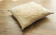 Poduszka jasiek z szydełkową aplikacją i pomponami.