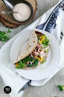 Pełnoziarnista tortilla z łososiem, papryką, czerwoną cebulą i mieszanką sałat. Polana lekkim sosem z jogurtu naturalnego, słodkiej papryki i czosnku. // Whole wheat tortilla wi...