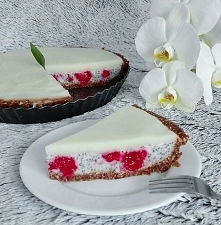 Na zdjęciu pyszna, słodka i owocowa tarta bez pieczenia: na spodzie z płatków owsianych, wiórków kokosowych i migdałów, druga warstwa to mleko kokosowe z chia i malinami, a na w...