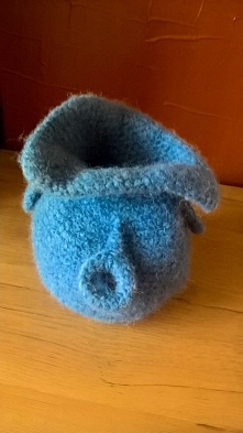 Taki niebieski przytulak może ocieplić pomieszczenie lub być świetnym prezentem. Sweterek dla szklanki, w którym kwiaty wyglądają niezwykle oryginalnie.