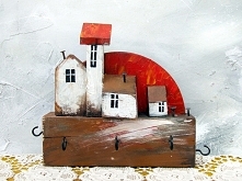 Urocze białe domki stoją na grubej brązowej belce - taki wieszak na klucze w naszej galerii.