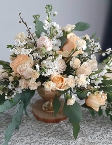 Brzoskwiniowy bukiet kwiatów w złotym pucharku.