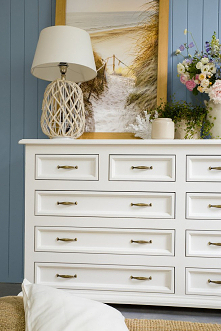 Biała duża komoda drewniana z szufladami do sypialni.