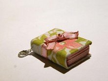 Sekretnik w tkaninowej okładce, ozdobiony satynową różową wstążeczką, wypełniony słodko-różowymi kartkami. Całość dopełniona karabińczykiem.