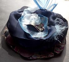 Piętnasta z kolekcji broszka granatowo - niebieska jest urocza. Wykonana została z tiulu, żorżety, satyny, organzy,materiału żakardowego i innych. 
Ozdobę broszki stanowi oponka...