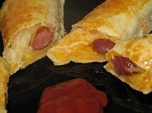 kabanosy lub parowki, ser zolty w plasterkach, ciasto francuskie,jajko do posmarowania wierzchu.