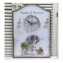 Zegar w stylu prowansalskim umieszczony na białej tabliczce z motywem lawendy, który wypełnia każde wolne miejsce. Prześliczna ścienna dekoracja.