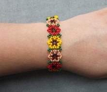 Lekka i bardzo kobieca, ręcznie wykonana bransoletka z koralików szklanych. Wzór w kolorowe kwiaty wzbogaci wiosenną stylizację!