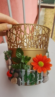 Osłonka na doniczkę.
Kamyczki z morza, sztuczne kwiaty z namiotu za 2 zł. No i klej na gorąco:-)