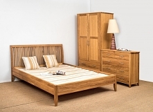 Zestaw drewnianych mebli do sypialni - łóżko, szafa i komoda.