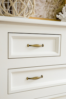 Biała duża komoda drewniana z szufladami do sypialni.